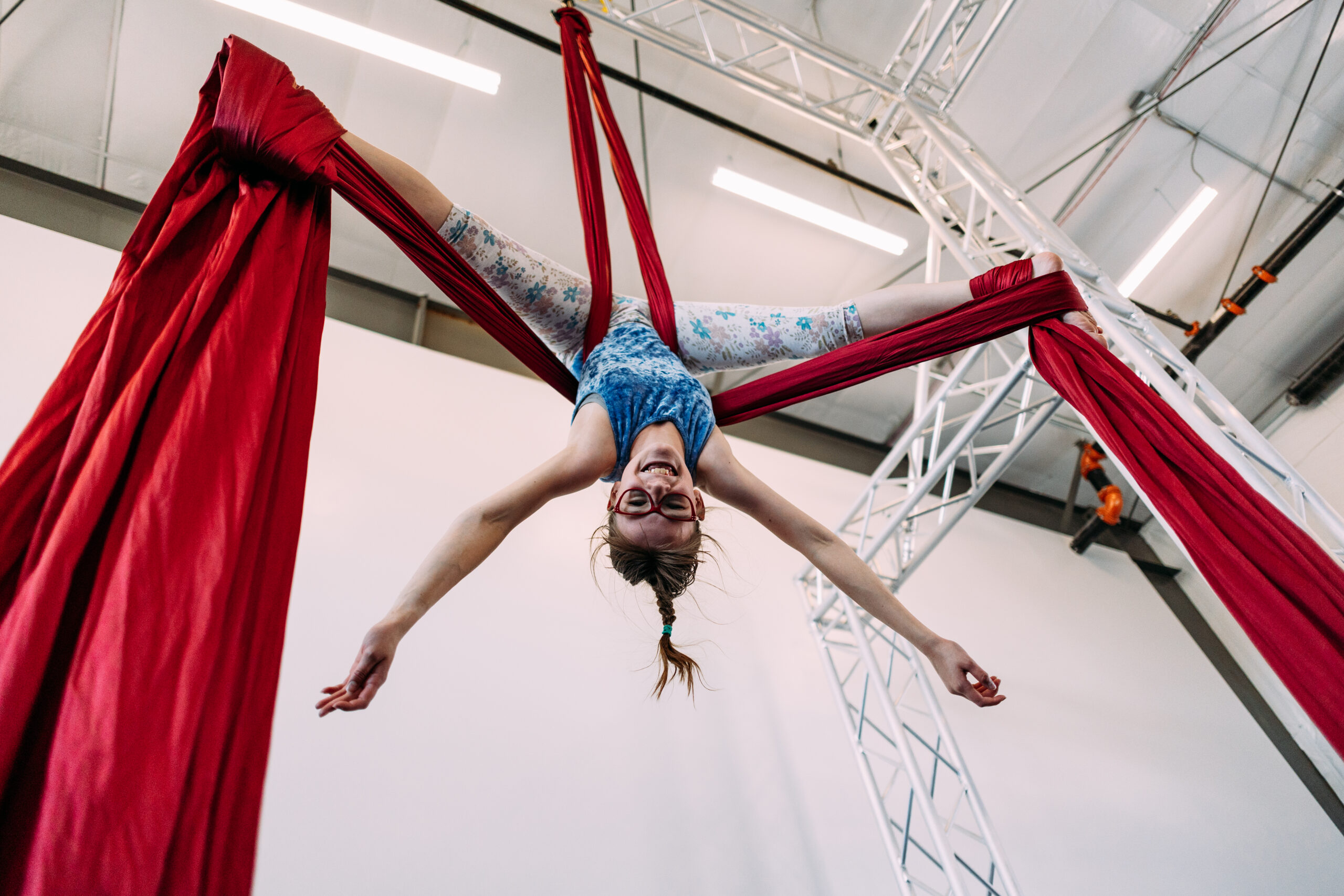 A pre-teen age child in an aerial silk upside down at aerial cirque over denver summer camp and pre teen dance class.