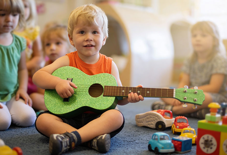 ACOD_toddler-boy-plays-a-small-glittery-guitar-orange--AerialCirqueOverDenver