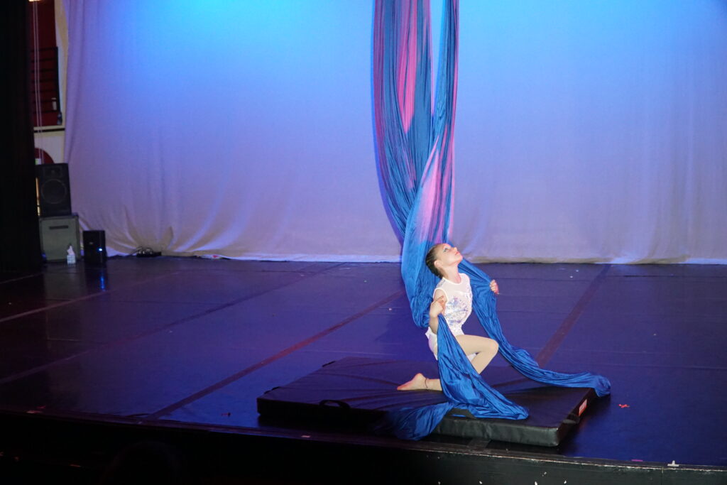 youth aerial silks dancer on a pose on the ground. Performing in a student showcase at Cleo parker robinson theatre.