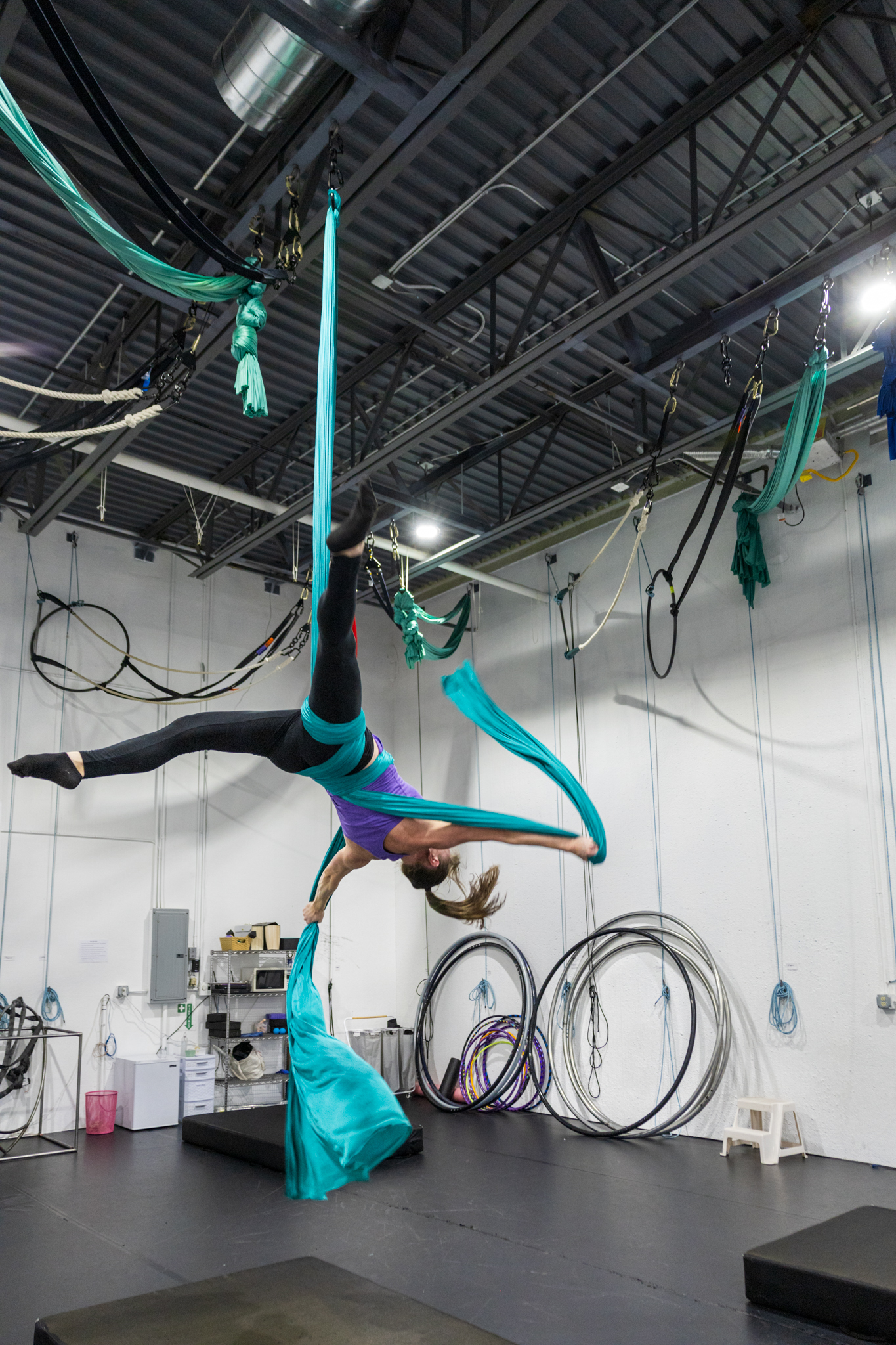 Aerial student at aerial cirque over denver doing a drop. She has a mat under her for aerial safety. This is during an adult dance class.