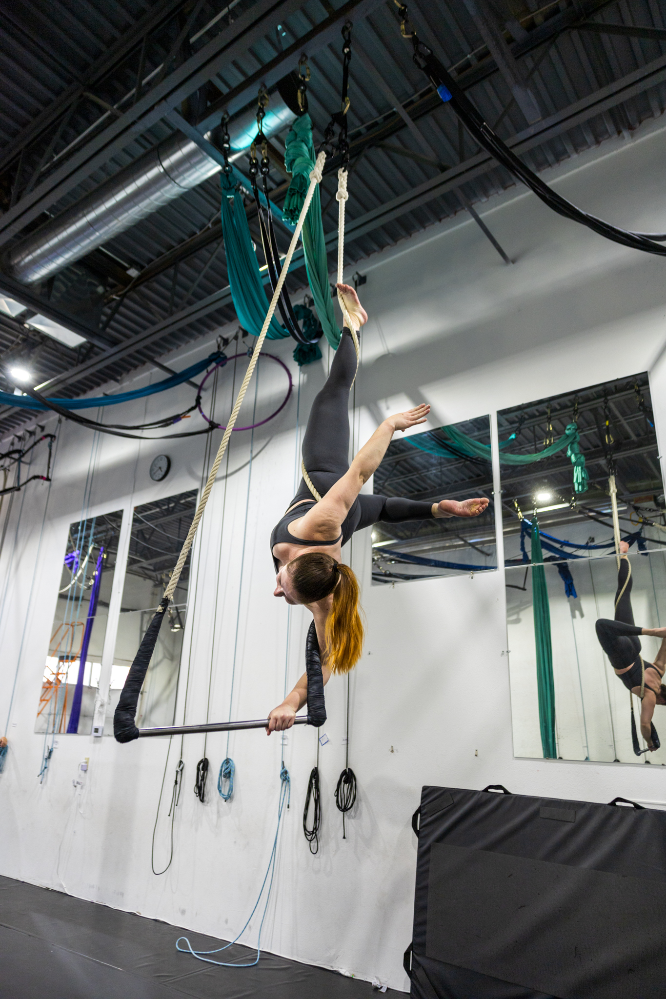 An intermediate aerial dance student on trapeze doing a handstand. Aerial cirque over denver offers all level adult dance classes and adult gymnastics classes.