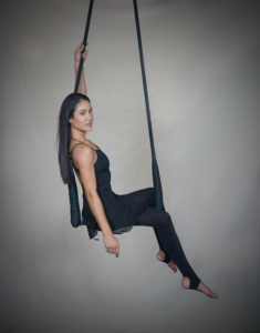 woman sitting on a trapeze at denver circus school